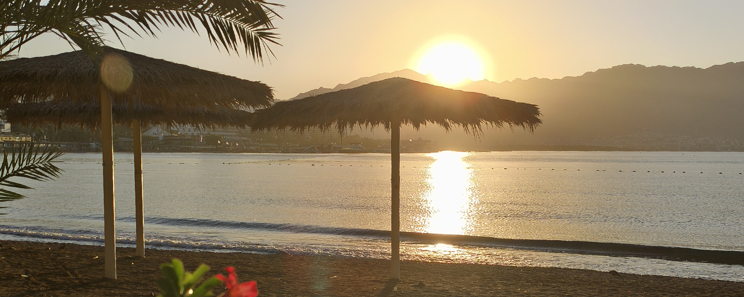 זריחה בחוף קיסוסקי באילת עם שמשיות קש
